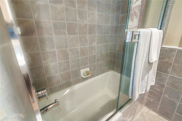 bathroom featuring combined bath / shower with glass door, tile patterned flooring, and tile walls