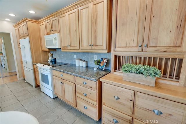 kitchen featuring white appliances, dark stone countertops, light brown cabinetry, decorative backsplash, and light tile patterned flooring