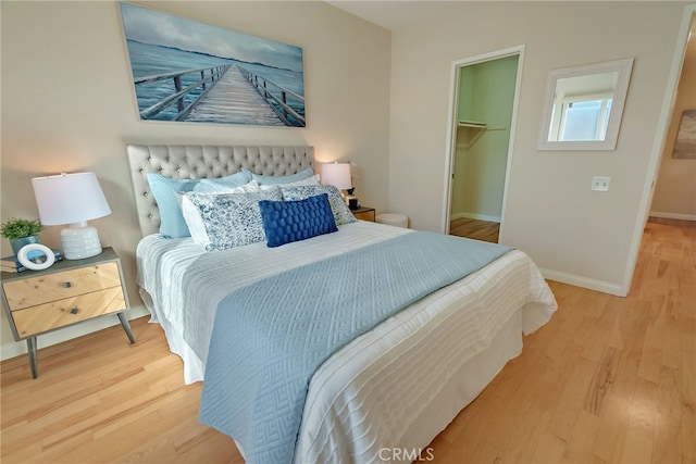 bedroom with light wood-type flooring, a walk in closet, and a closet