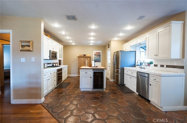 kitchen featuring tasteful backsplash, white cabinetry, appliances with stainless steel finishes, butcher block counters, and beverage cooler