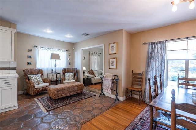 sitting room featuring dark wood-type flooring and a healthy amount of sunlight