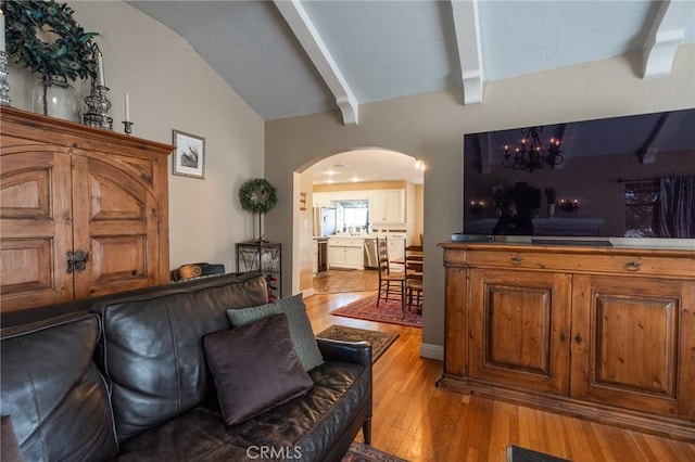 living room with vaulted ceiling with beams, a chandelier, and light hardwood / wood-style floors