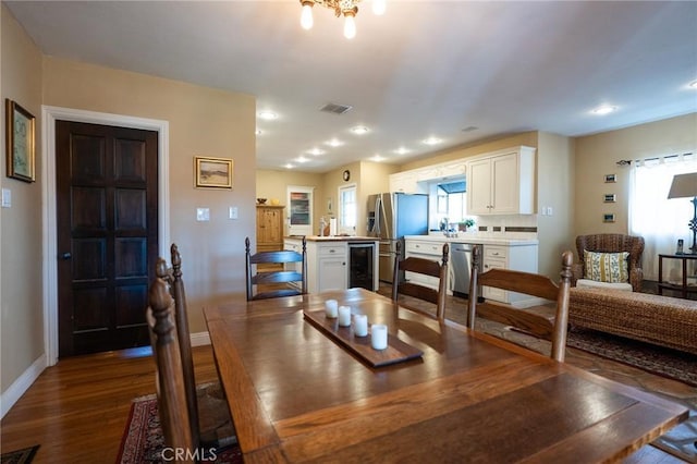 dining space featuring hardwood / wood-style flooring, beverage cooler, and a healthy amount of sunlight