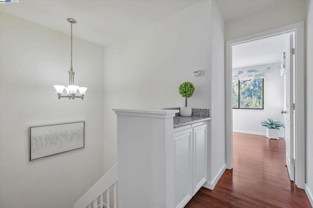 hall featuring dark wood-type flooring and an inviting chandelier