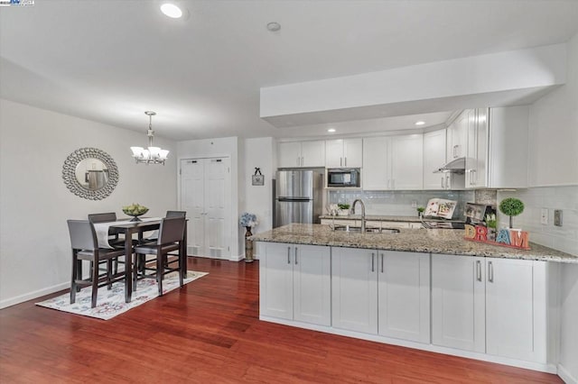 kitchen with light stone countertops, white cabinetry, tasteful backsplash, stainless steel fridge, and built in microwave