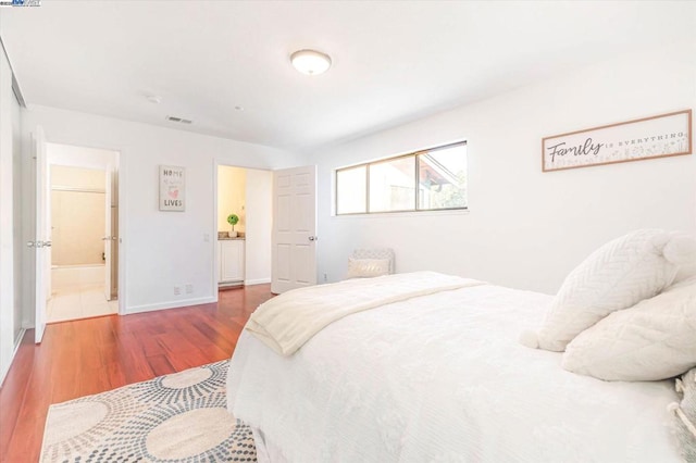 bedroom with wood-type flooring and connected bathroom