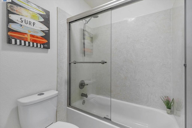 bathroom with toilet and shower / bath combination with glass door