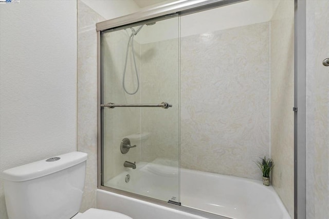 bathroom with toilet and shower / bath combination with glass door