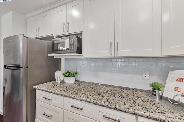 kitchen featuring decorative backsplash, light stone countertops, white cabinetry, and stainless steel fridge