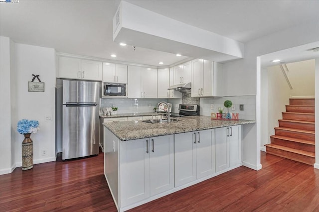 kitchen with white cabinets, stainless steel appliances, kitchen peninsula, and sink