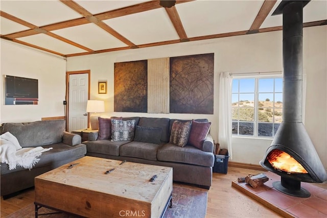 living room with beam ceiling, coffered ceiling, a wood stove, and hardwood / wood-style floors