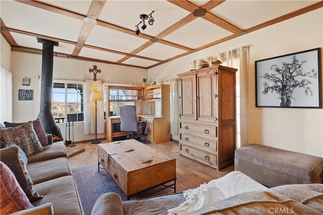 living room featuring light wood-type flooring, beam ceiling, a wood stove, and coffered ceiling