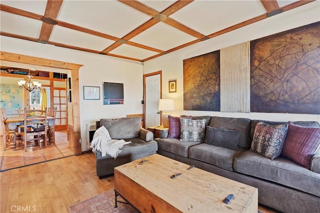 living room featuring wood-type flooring, a notable chandelier, beamed ceiling, and coffered ceiling