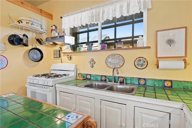 kitchen featuring white cabinets, sink, tile countertops, and white gas range oven