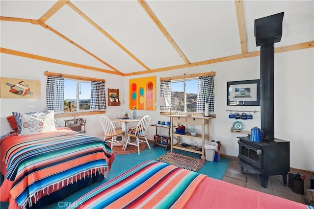 bedroom featuring vaulted ceiling, a wood stove, and multiple windows