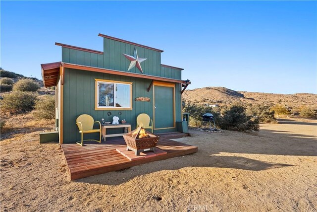 back of house with a mountain view and a fire pit