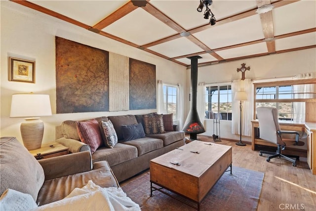 living room featuring wood-type flooring, beamed ceiling, coffered ceiling, and a wood stove