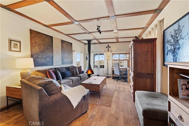 living room featuring light wood-type flooring, a wood stove, beam ceiling, and coffered ceiling