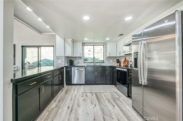 42893 Long Hollow Dr, Coarsegold, CA 93614 - kitchen featuring decorative backsplash, sink, white cabinetry, light hardwood / wood-style flooring, and stainless steel appliances