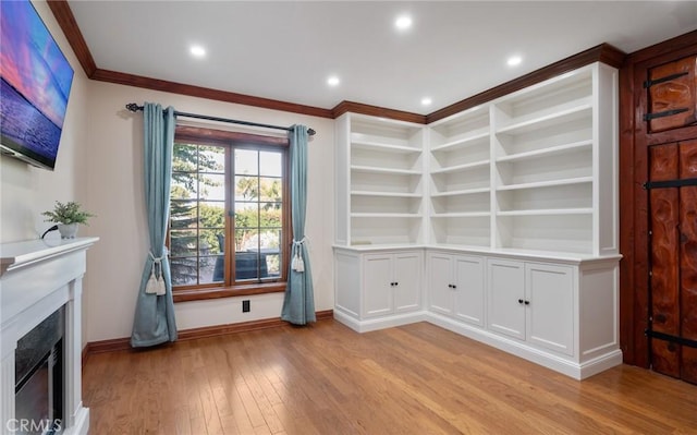 interior space with built in shelves, light wood-type flooring, and ornamental molding