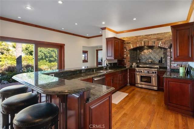 kitchen featuring appliances with stainless steel finishes, kitchen peninsula, dark stone counters, and sink