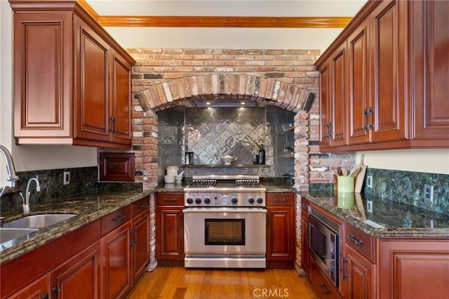 kitchen featuring appliances with stainless steel finishes, dark stone countertops, and ornamental molding