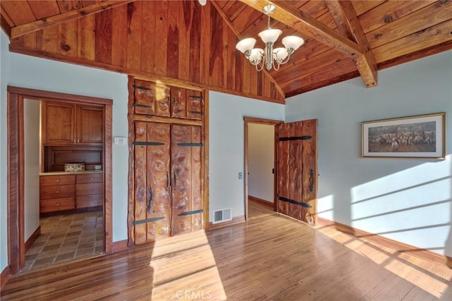 unfurnished living room featuring wooden ceiling, hardwood / wood-style floors, lofted ceiling with beams, and a notable chandelier