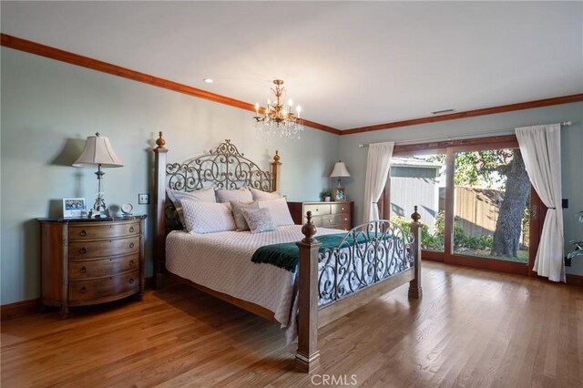 bedroom featuring access to outside, wood-type flooring, crown molding, and a notable chandelier