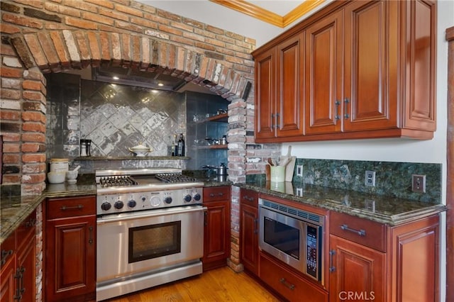 kitchen with appliances with stainless steel finishes, dark stone countertops, and backsplash