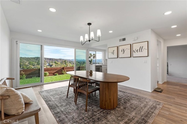 dining area with a notable chandelier, a mountain view, and light hardwood / wood-style flooring