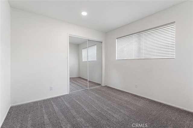 unfurnished bedroom with a closet and dark colored carpet