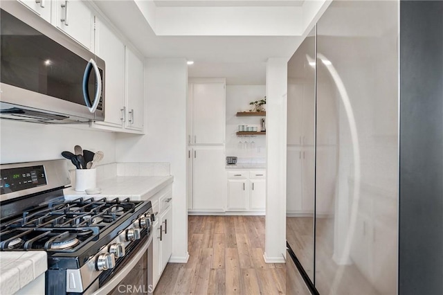 kitchen with light hardwood / wood-style floors, white cabinets, and appliances with stainless steel finishes