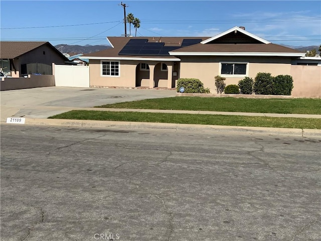 view of front of property featuring a front lawn and solar panels