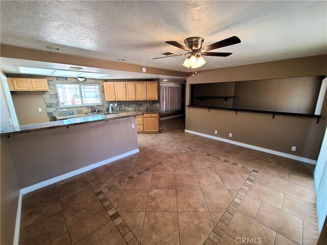 kitchen featuring tasteful backsplash, a skylight, light tile patterned flooring, and ceiling fan