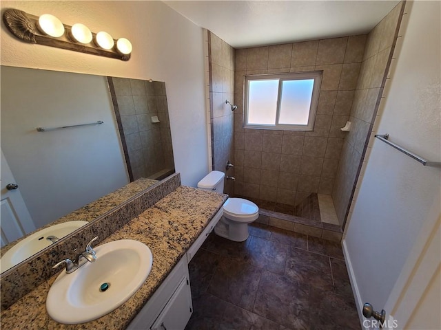 bathroom with toilet, vanity, and tiled shower