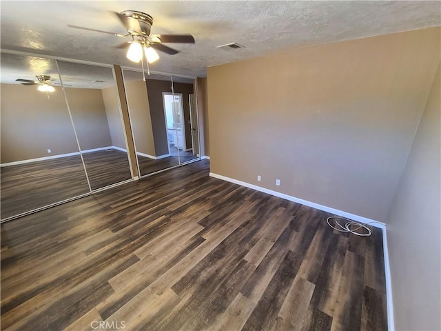 unfurnished bedroom featuring a textured ceiling, ceiling fan, dark hardwood / wood-style flooring, and a closet