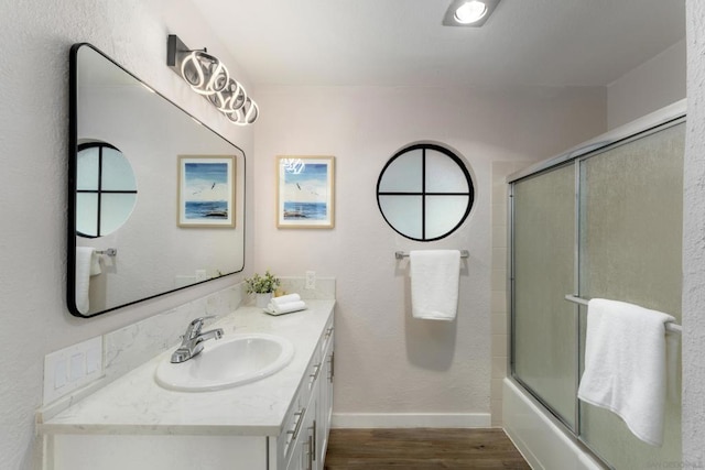 bathroom featuring hardwood / wood-style flooring, vanity, and shower / bath combination with glass door