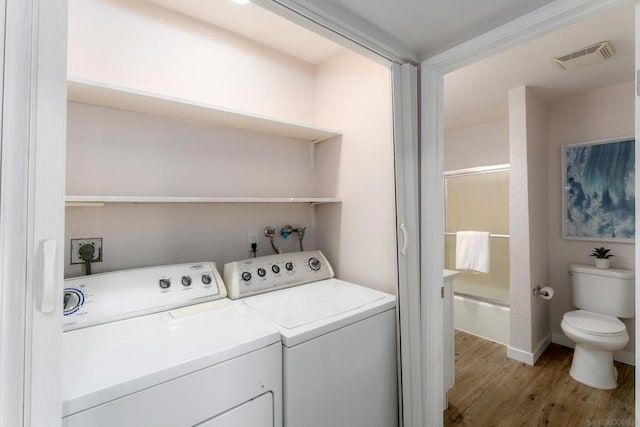 laundry area featuring separate washer and dryer and light hardwood / wood-style floors