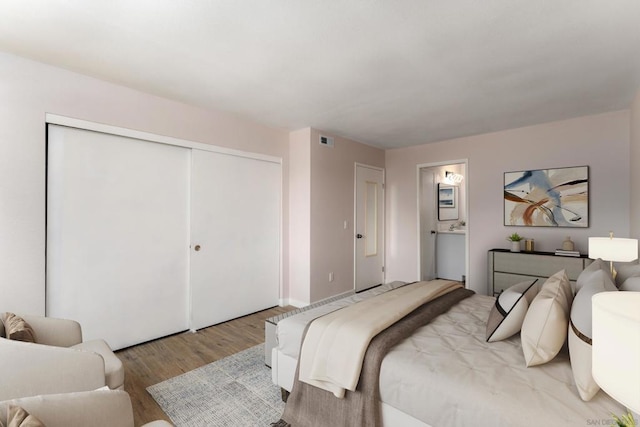 bedroom with ensuite bathroom, a closet, and light hardwood / wood-style floors