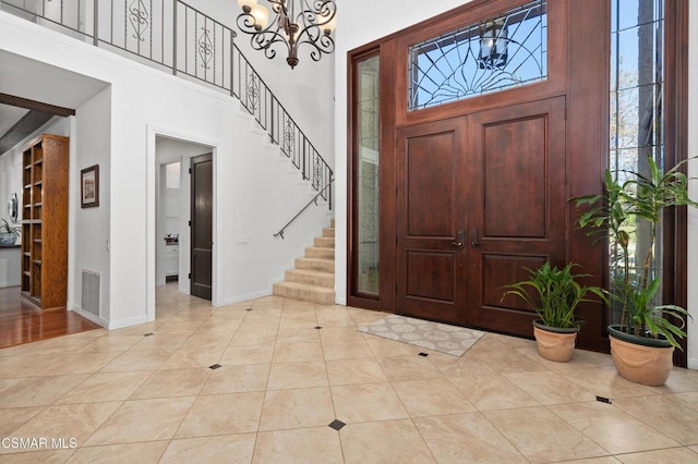 tiled entrance foyer featuring a high ceiling and a notable chandelier