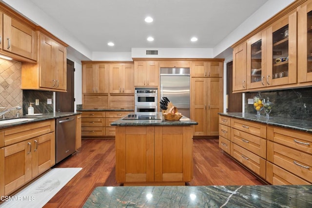 kitchen with dark hardwood / wood-style floors, appliances with stainless steel finishes, tasteful backsplash, and a kitchen island