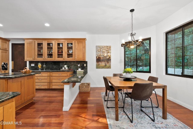 kitchen with an inviting chandelier, black electric stovetop, decorative backsplash, decorative light fixtures, and dark wood-type flooring