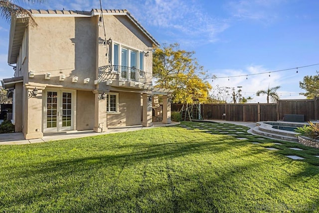 back of property featuring a balcony, a yard, and a patio