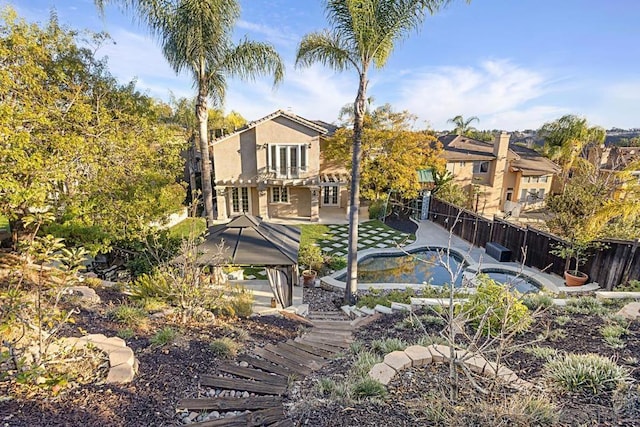 rear view of property featuring a gazebo, a hot tub, and a patio