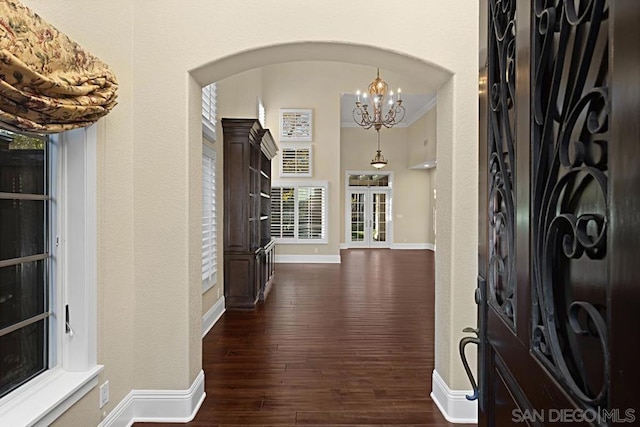 foyer featuring dark hardwood / wood-style flooring, crown molding, and a notable chandelier