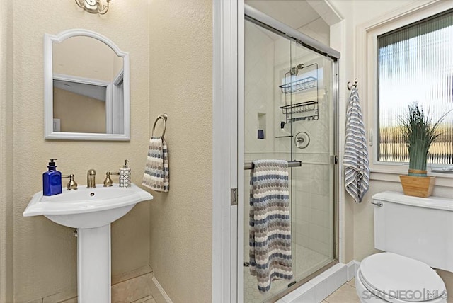 bathroom with sink, tile patterned floors, a shower with door, and toilet