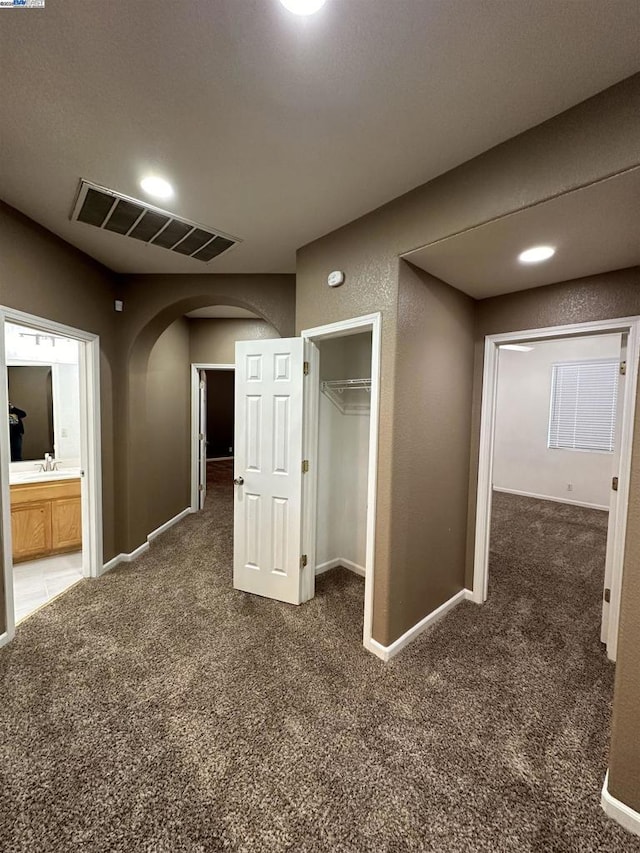 corridor featuring sink and dark colored carpet