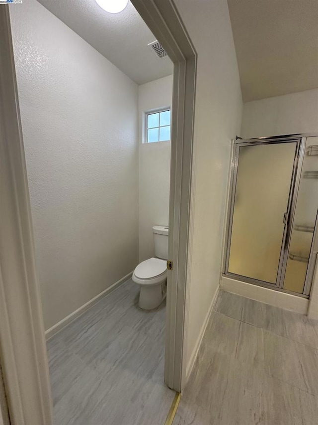 bathroom with wood-type flooring, toilet, and an enclosed shower