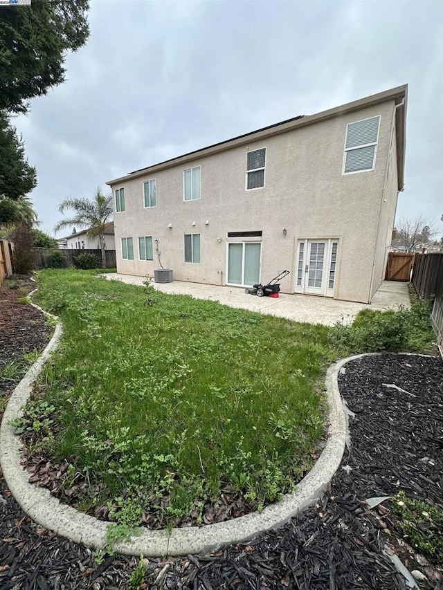 rear view of house with central AC unit, a patio area, and a lawn