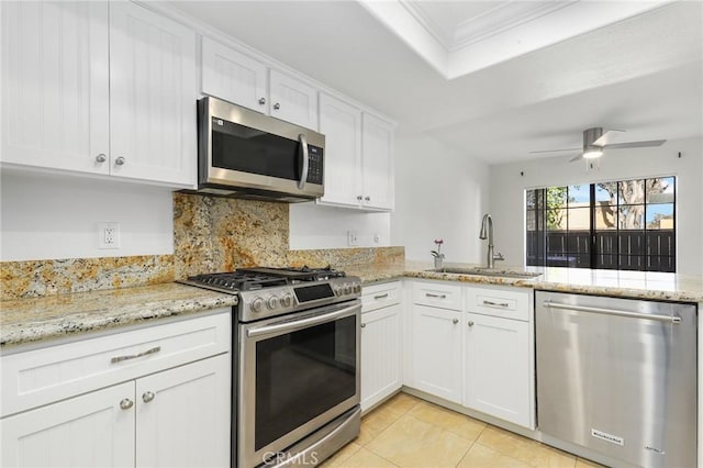 kitchen with appliances with stainless steel finishes, tasteful backsplash, light tile patterned floors, white cabinets, and light stone counters